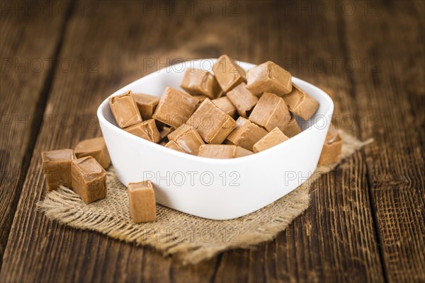 Portion of homemade Caramel on wooden background (selective focus, close-up shot)