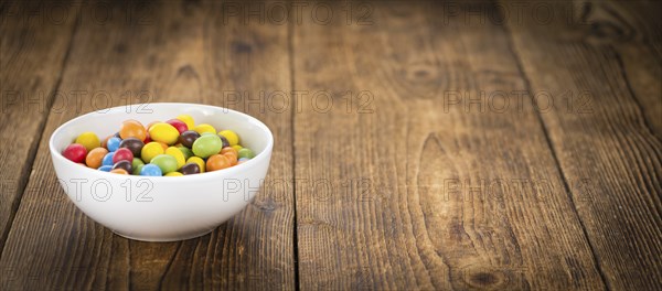 Cocolate coated Peanuts on an old wooden table as detailed close-up shot (selective focus)
