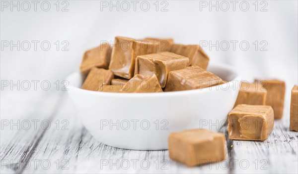 Portion of homemade Caramel on wooden background (selective focus, close-up shot)