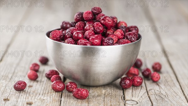 Healthy Cranberries (dried) on a wooden table as detailed close-up shot (selective focus)
