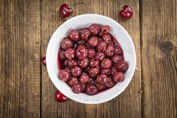 Canned Cherries as high detailed close-up shot on a vintage wooden table, selective focus