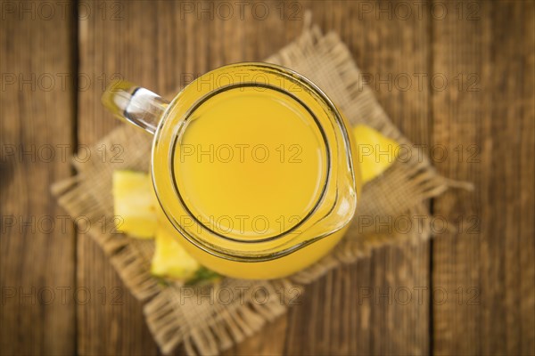 Pineapple Juice as high detailed close-up shot on a vintage wooden table, selective focus