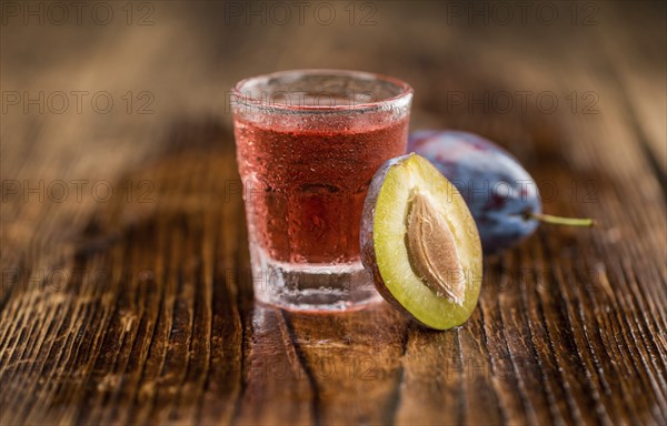 Plum Liqueur on rustic wooden background as close-up shot
