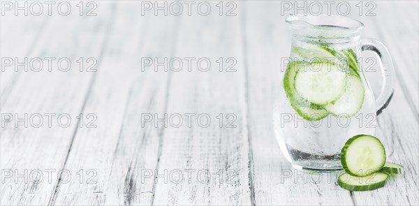 Fresh made Cucumber Water as high detailed close-up shot on a vintage wooden table, selective focus