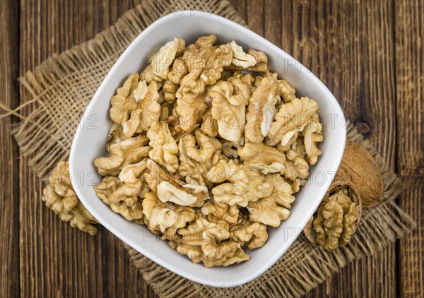 Walnuts (kernels) on an old wooden table as detailed close-up shot (selective focus)