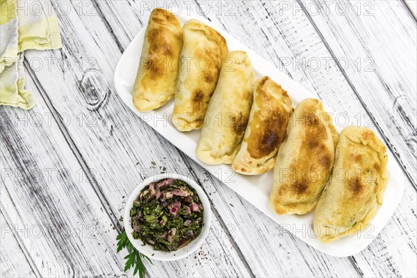 Wooden table with fresh homemade Empanadas (detailed close-up shot, selective focus)