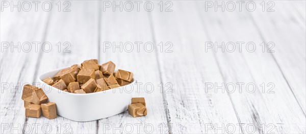 Caramel pieces as high detailed close-up shot on a vintage wooden table (selective focus)