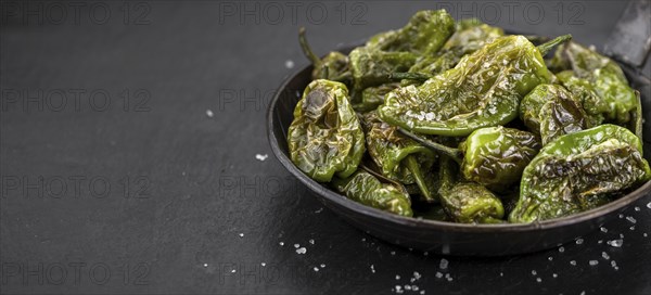 Some Pimientos de Padron on a slate slab as detailed close-up shot, selective focus