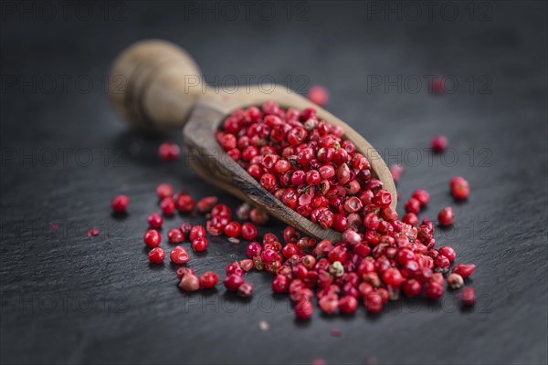 Portion of Pink Peppercorns on a rustic slate slab, selective focus, close-up shot