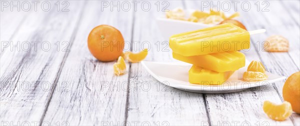 Homemade Tangerine Popsicles with some fresh fruits (close-up shot) on a vintage background