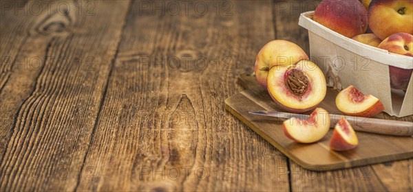 Fresh Peaches as high detailed close-up shot on a vintage wooden table, selective focus