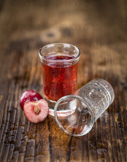 Cherry Liqueur as high detailed close-up shot on a vintage wooden table, selective focus