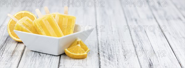 Some homemade orange popsicles (selective focus) on a vintage background