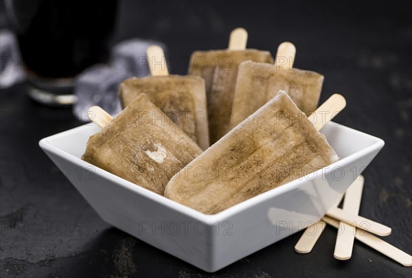 Slate slab with cola popsicles (homemade) as detailed close-up shot (selective focus)