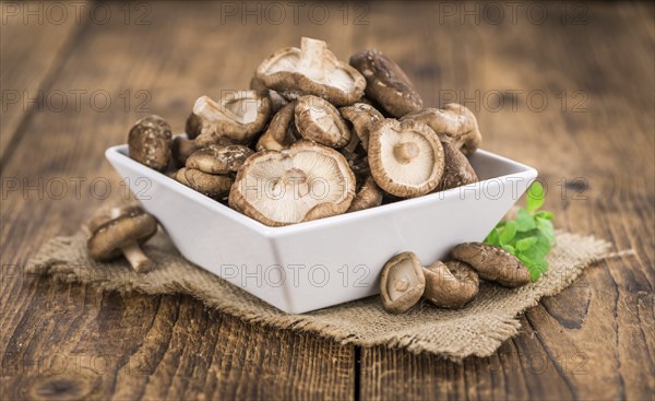 Shiitake mushrooms on an old wooden table as detailed close-up shot, selective focus