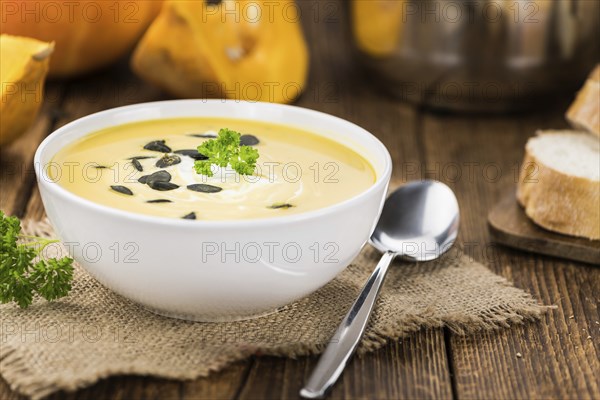 Homemade Pumpkin Soup (selective focus) on rustic background as close-up shot