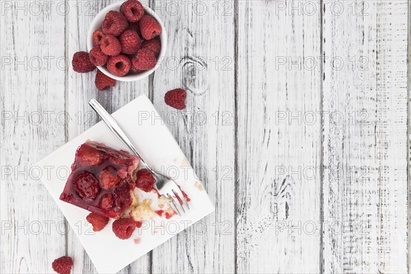 Piece of Raspberry Cake on an old wooden table (selective focus, close-up shot)