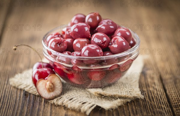 Preserved Cherries on an old wooden table as detailed close-up shot, selective focus