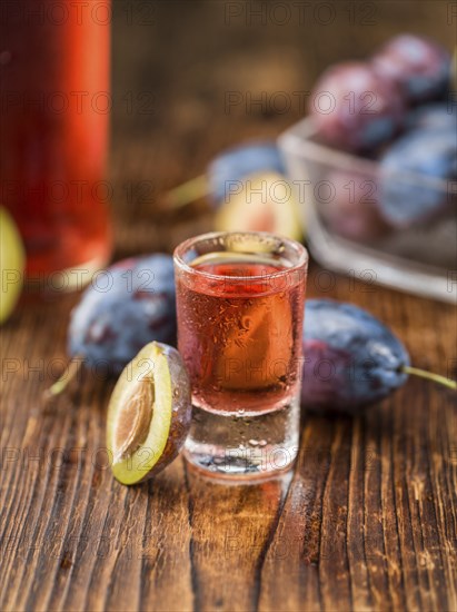 Homemade Plum Liqueur on an wooden table as detailed close-up shot, selective focus