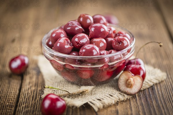 Canned Cherries as high detailed close-up shot on a vintage wooden table, selective focus