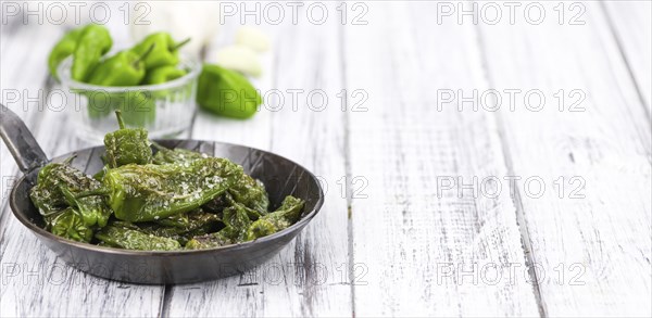 Pimientos de Padron on rustic wooden background as close-up shot