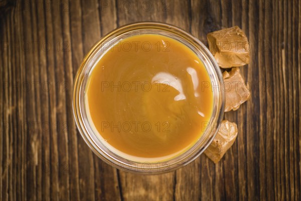 Caramel Sauce on an old wooden table as detailed close-up shot (selective focus)
