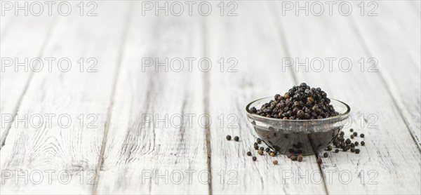 Preserved black Peppercorns on wooden background, selective focus, close-up shot