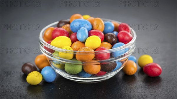 Portion of Cocolate coated Peanuts on a rustic slate slab (selective focus, close-up shot)