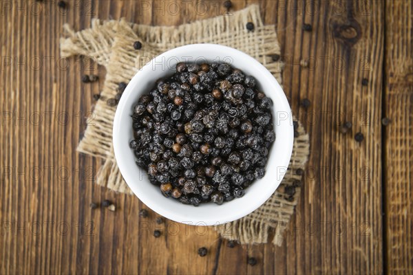 Preserved black Peppercorns on wooden background, selective focus, close-up shot