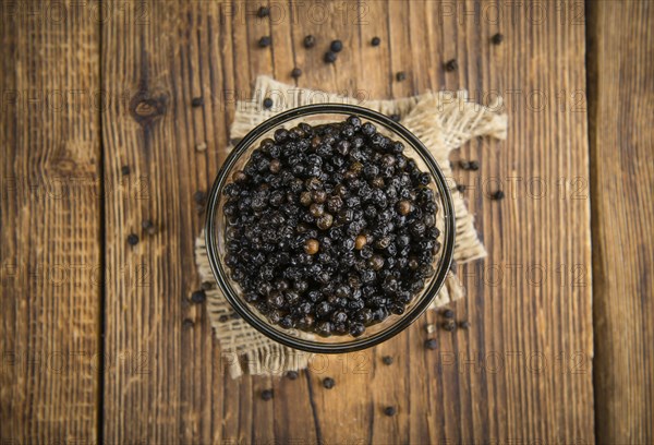Black Peppercorns preserved on wooden background, selective focus, close-up shot