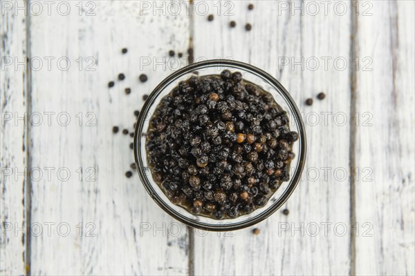 Preserved black Peppercorns on a wooden table as close-up shot