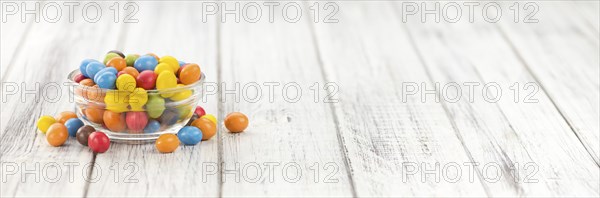 Cocolate coated Peanuts on rustic wooden background (close-up shot)