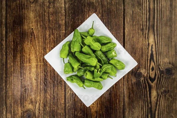 Raw Pimientos on an old wooden table as detailed close-up shot, selective focus