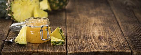 Pineapple Jam as high detailed close-up shot on a vintage wooden table, selective focus