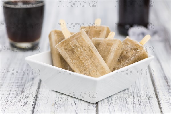 Fresh made Cola Popsicles on wooden background (selective focus, close-up shot)