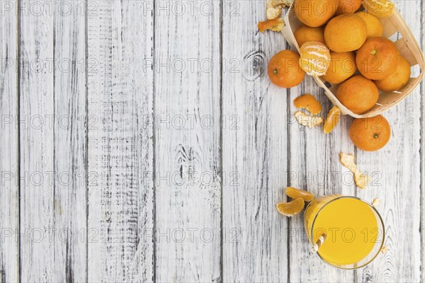 Wooden table with fresh homemade Tangerine Juice (close-up shot, selective focus)