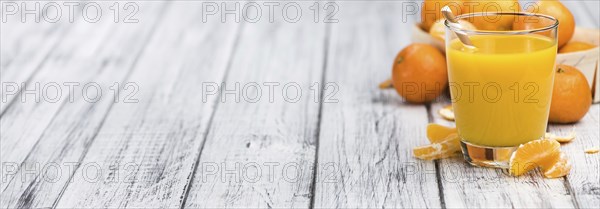 Homemade Tangerine Juice on an old and rustic wooden table (selective focus, close-up shot)