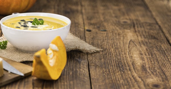 Portion of fresh made Pumpkin Soup (close-up shot) on rustic background