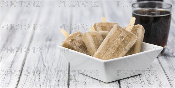 Fresh made Cola Popsicles on wooden background (selective focus, close-up shot)