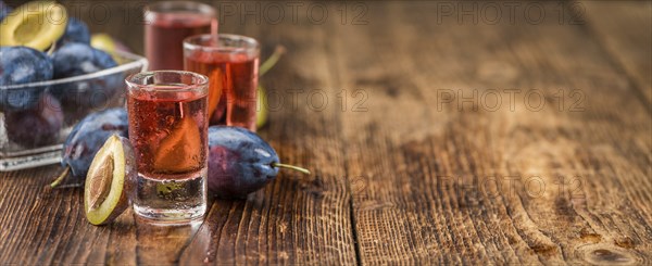 Homemade Plum Liqueur on an wooden table as detailed close-up shot, selective focus