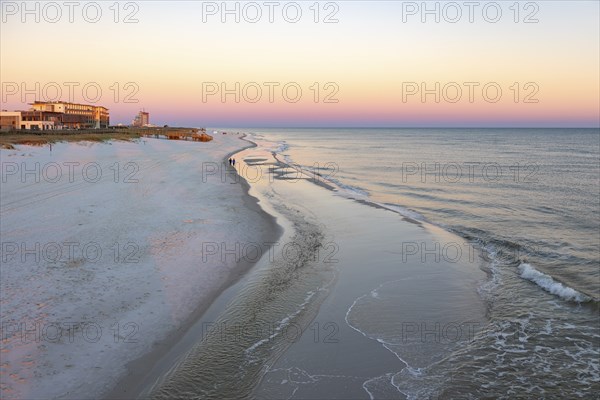 Tow women walking along the Gulf of Mexico beach as the sun rises over the Gulf of Mexico at Gulf
