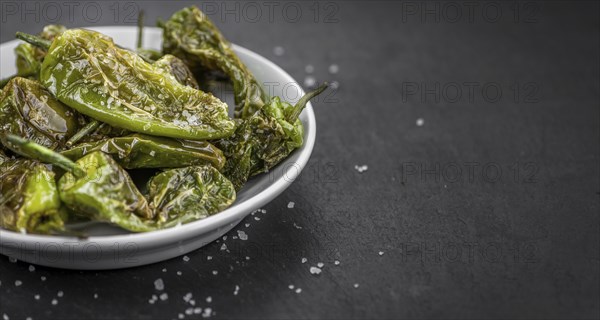 Portion of Pimientos de Padron on a rustic slate slab, selective focus, close-up shot
