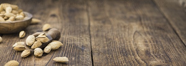 Roasted Almonds (in shell) on an old wooden table (close-up shot, selective focus)