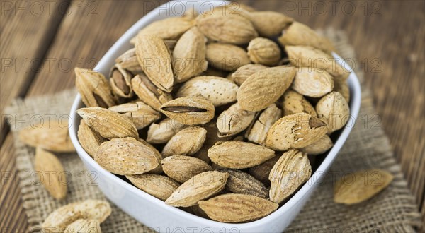 Roasted and salted Almonds (with shell) on a vintage background (close-up shot)