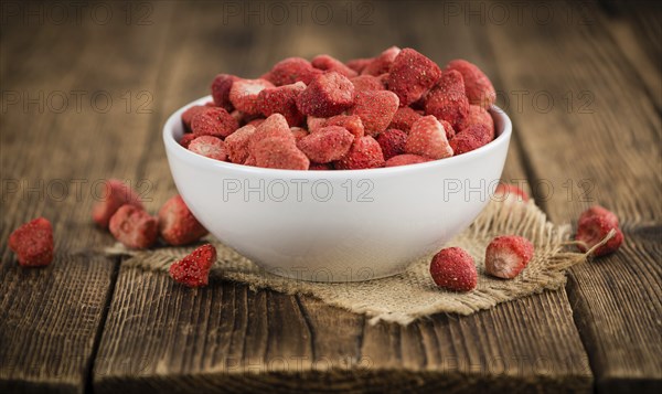 Strawberries (dried) as high detailed close-up shot on a vintage wooden table, selective focus