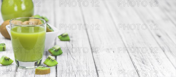 Wooden table with fresh made Kiwi Smoothie (close-up shot, selective focus)