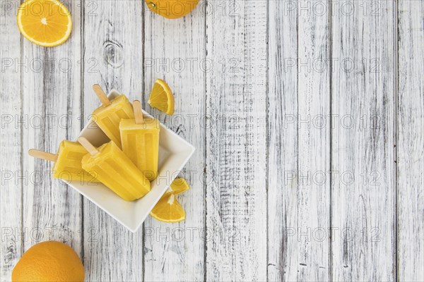 Some fresh made Popsicles (close-up shot, selective focus) on a wooden background