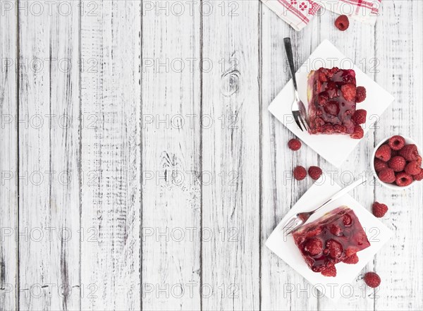 Fresh made portion of Raspberry Cake (selective focus, close-up shot) on rustic background