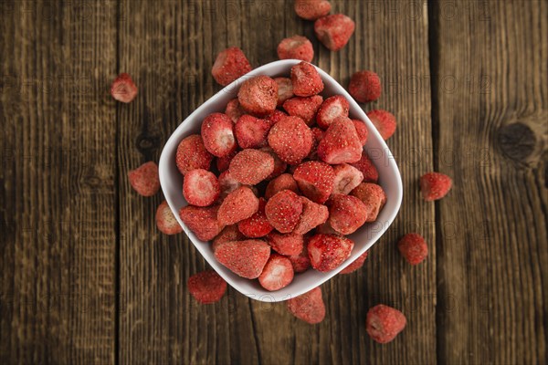 Strawberries (dried) as high detailed close-up shot on a vintage wooden table, selective focus
