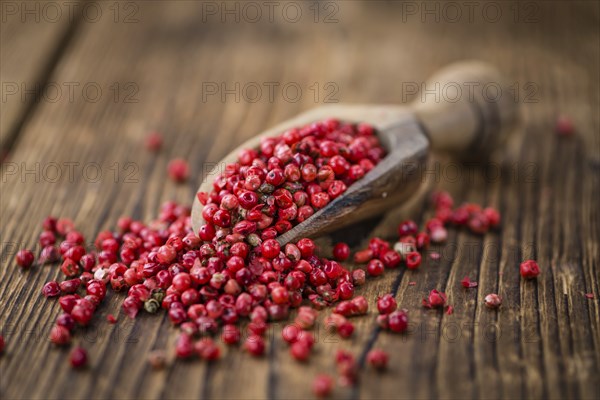 Pink Peppercorns on an old wooden table as detailed close-up shot, selective focus